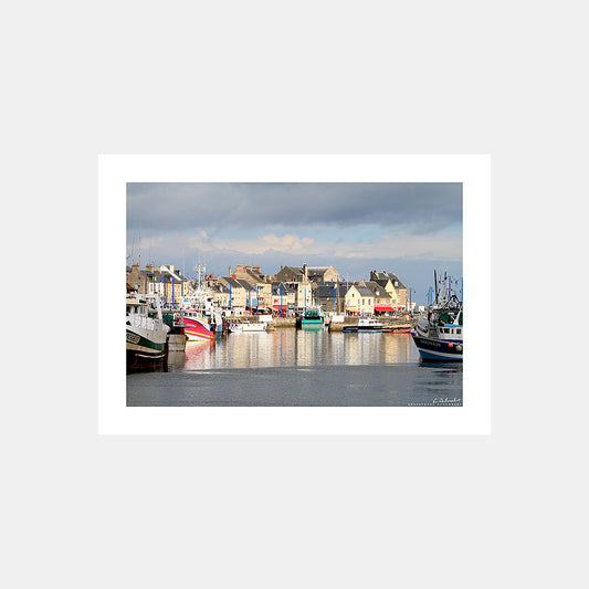 Photographie des maisons sur les quais et des bateaux de pêche de Port-en-Bessin sous un soleil d'orage, Calvados, Normandie, France.