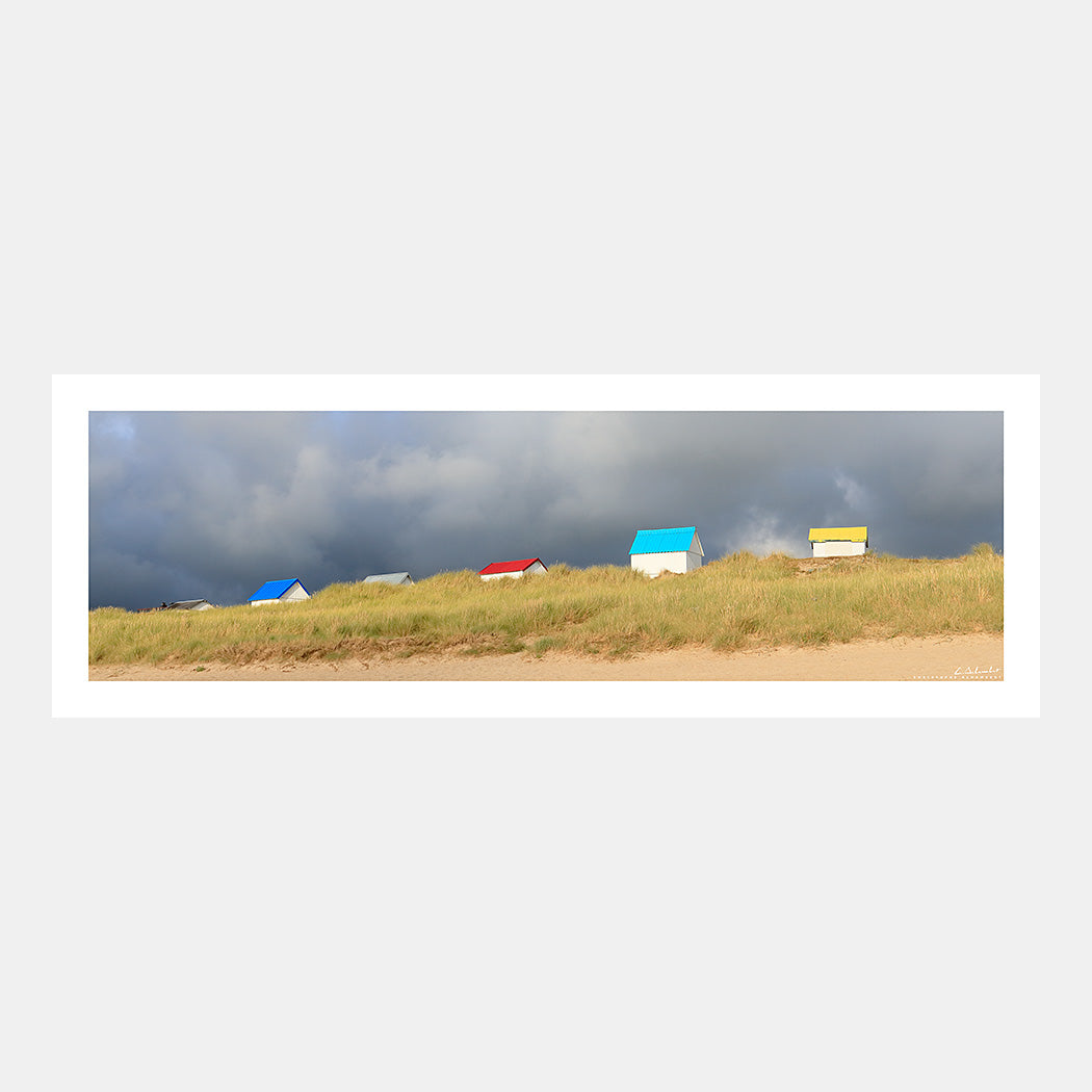 Photographie panoramique des cabines de plage aux toits colorés dans les dunes de Gouville-sur-Mer, Cotentin, Manche, Normandie, France.