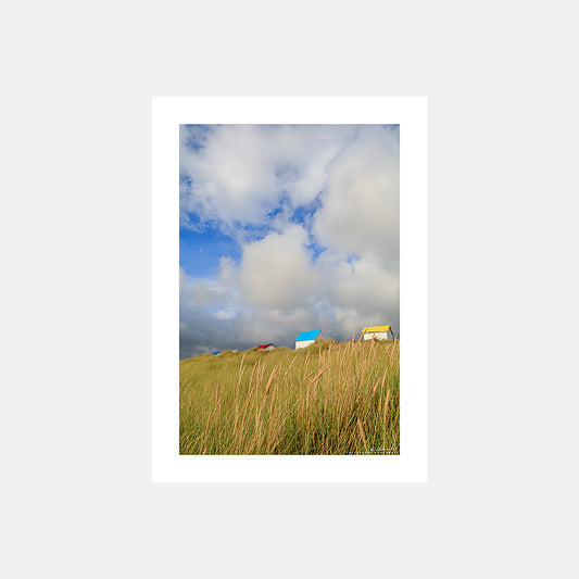 Photographie des dunes, oyats et cabines de plage de Gouville-sur-Mer aux toits bleus, rouges et jaunes, Cotentin, Manche, Normandie, France.