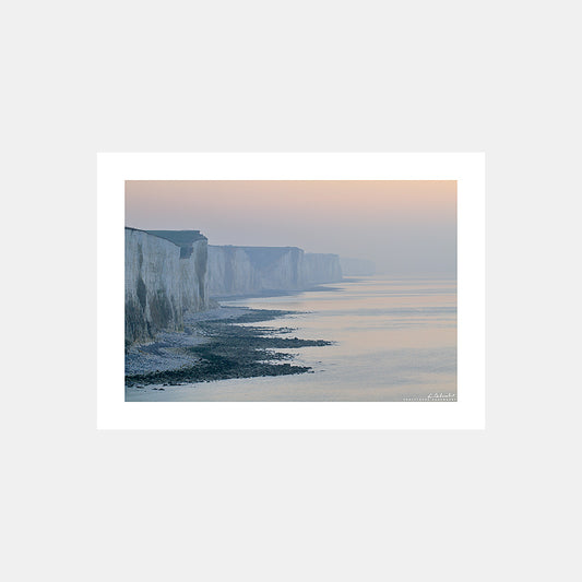 Photographie de la ligne des falaises picardes dans la brume orangée du crépuscule depuis Ault, Côte Picarde, Somme, Hauts-de-France, France.